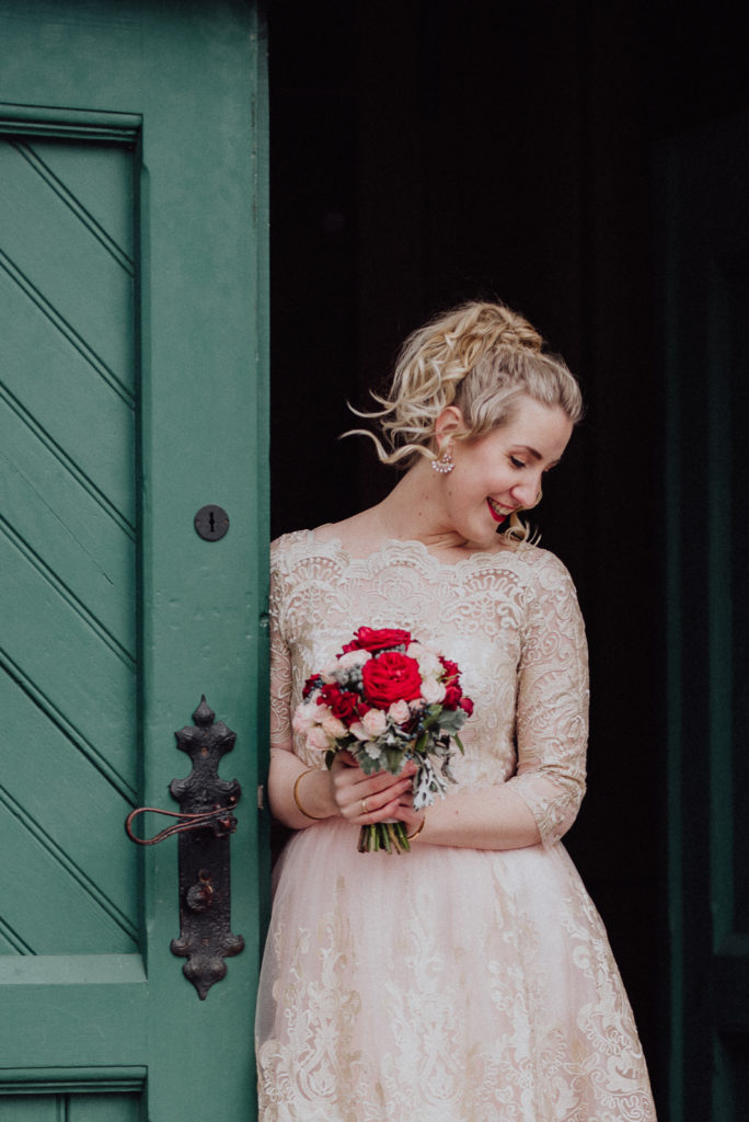 Wunderschöne Braut im Türrahmen der Zeche Zollern mit Blumenstrauss von Runo