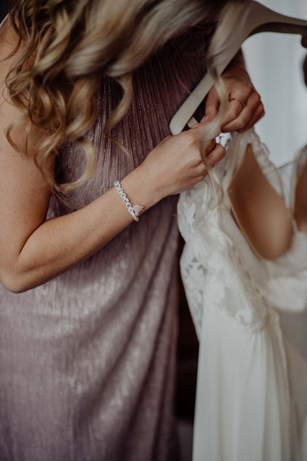 Eine helfende Hand durch die beste Freundin beim Ankleiden der Braut